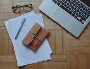 Flatlay with laptop, glasses, sketches and book